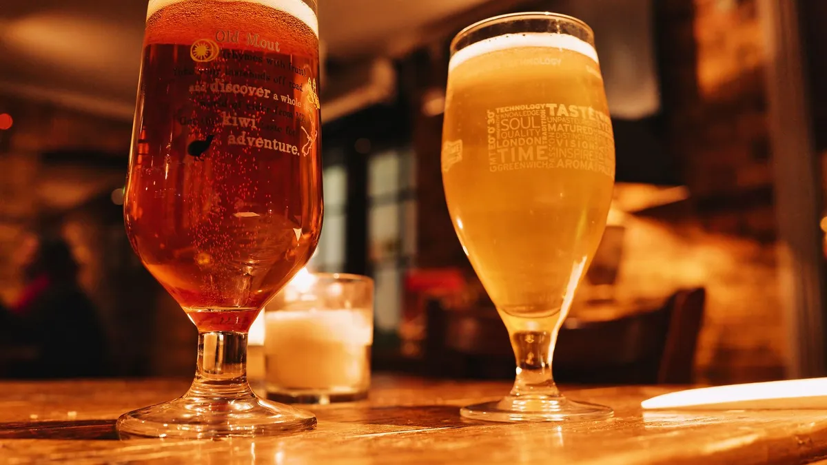 Two pints of lager on a wooden bar counter
