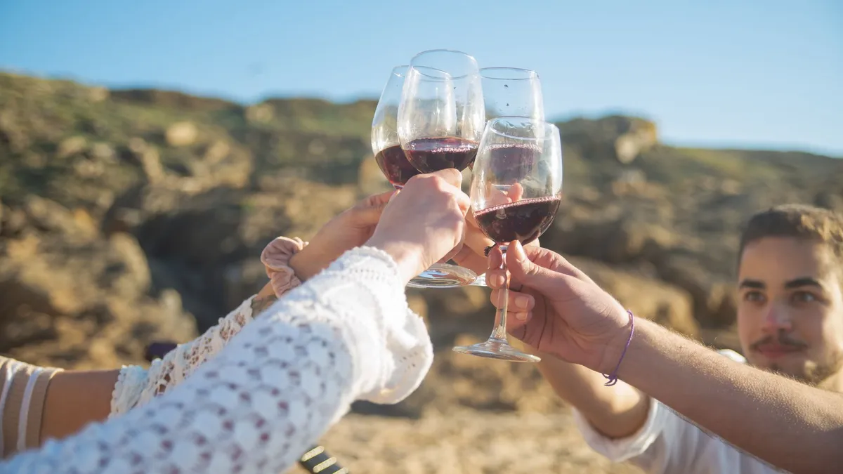 Group of friends raising glasses of red wine together at a dinner table