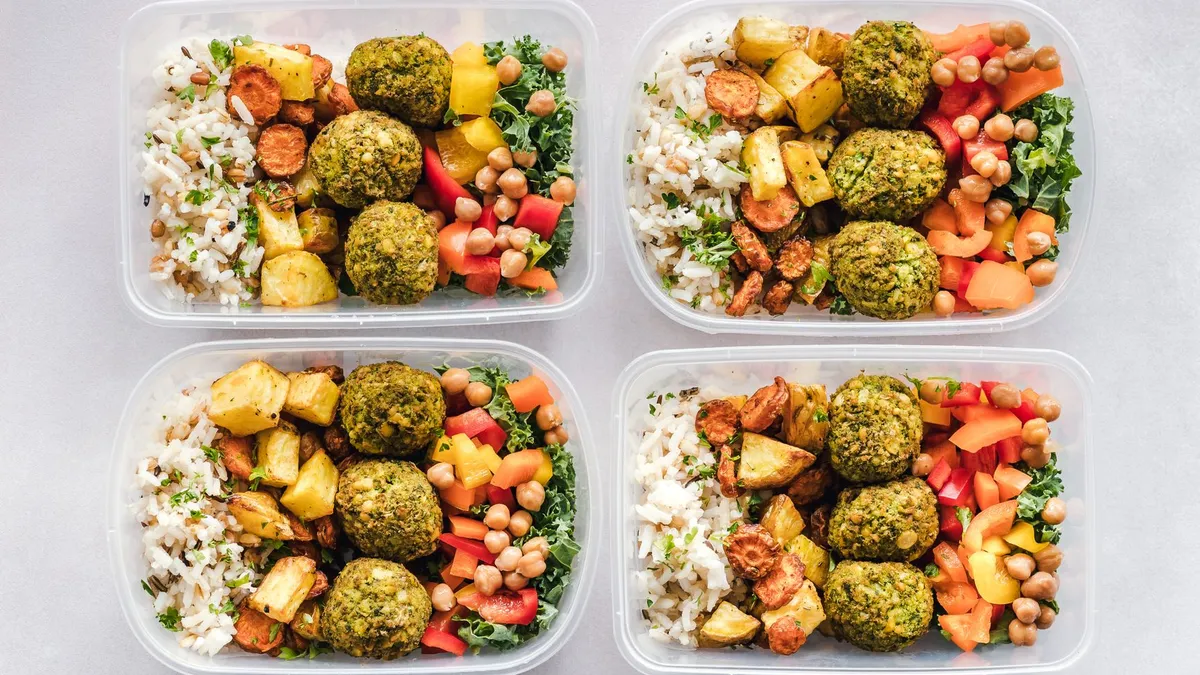 Several glass containers filled with balanced portions of chicken, rice and vegetables on a kitchen counter