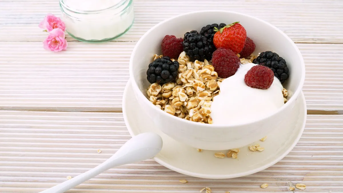 Un bol de porridge garni de framboises fraîches et de graines sur une table en bois