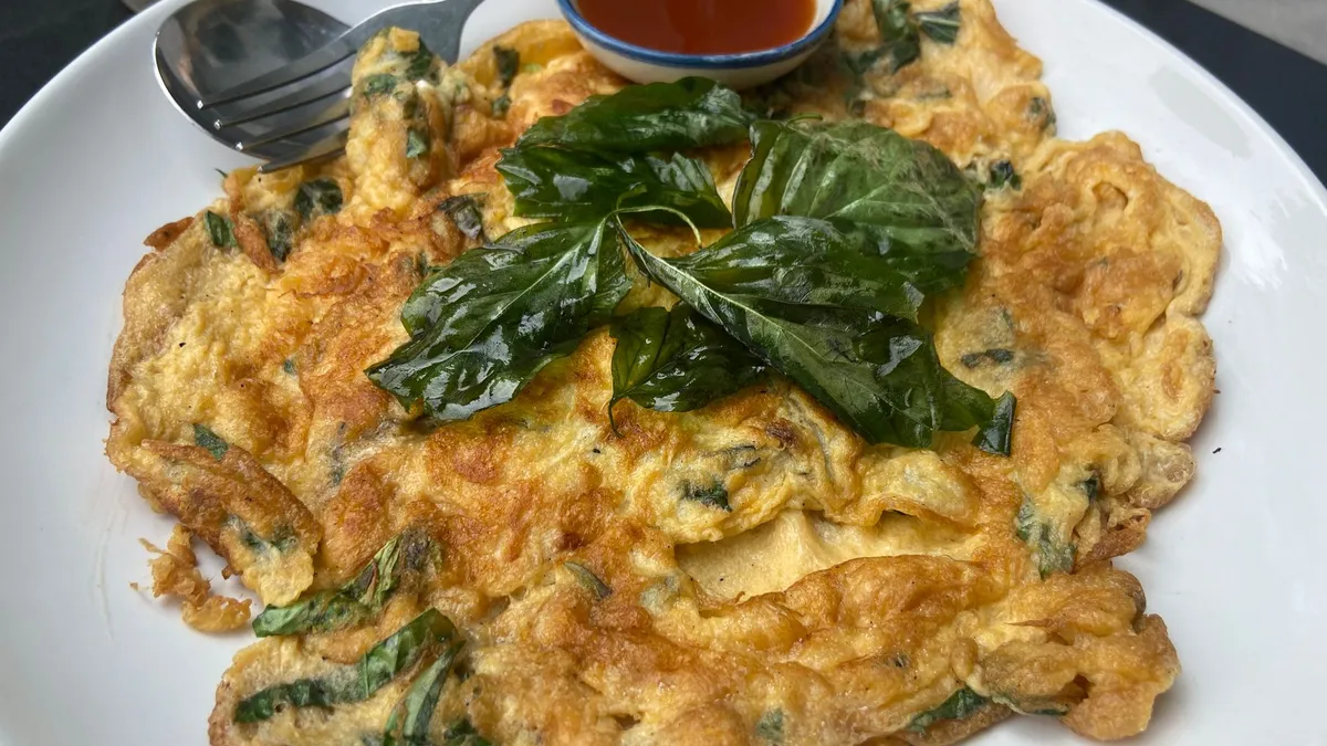 A plate of scrambled eggs with spinach and tomatoes on wholegrain toast