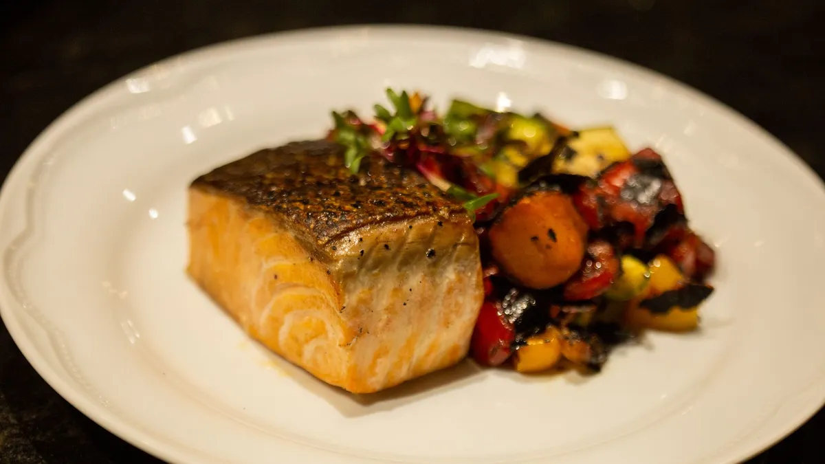 A plate of grilled salmon with green vegetables served at a restaurant