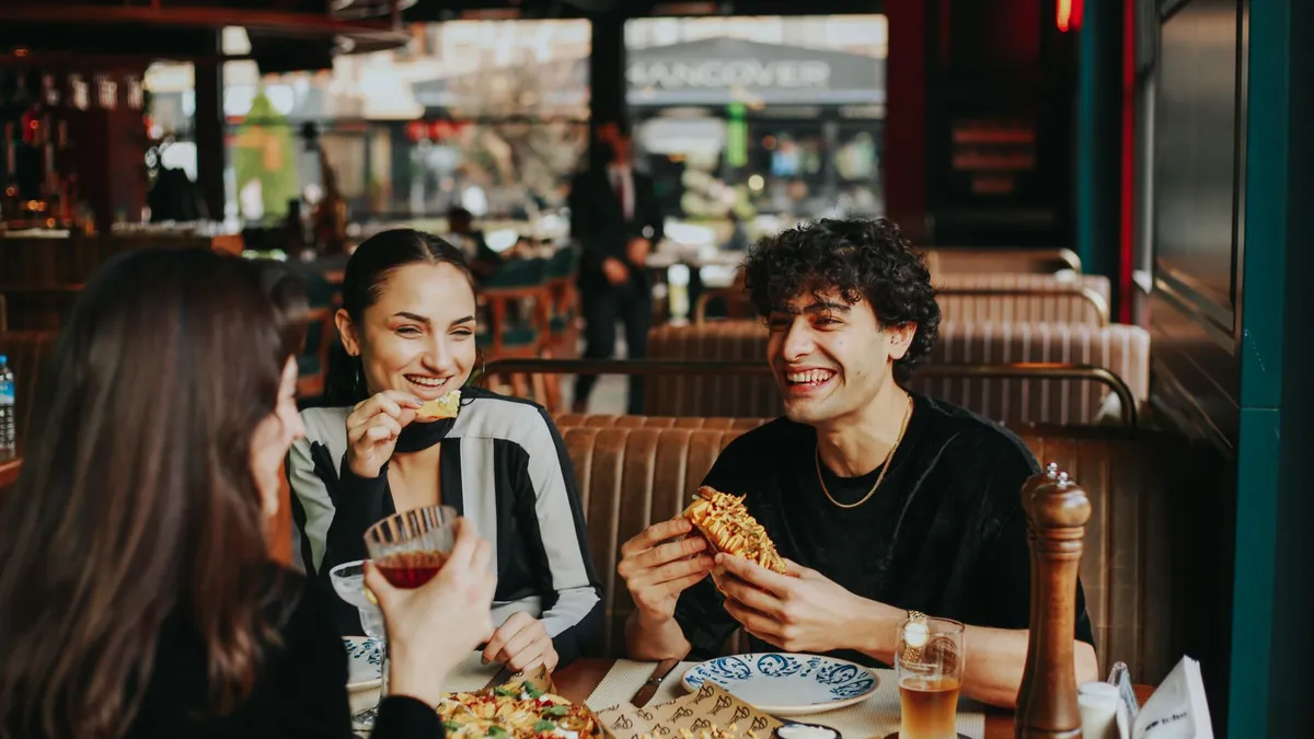 Friends sharing a meal at a restaurant table with plates of food and glasses of water