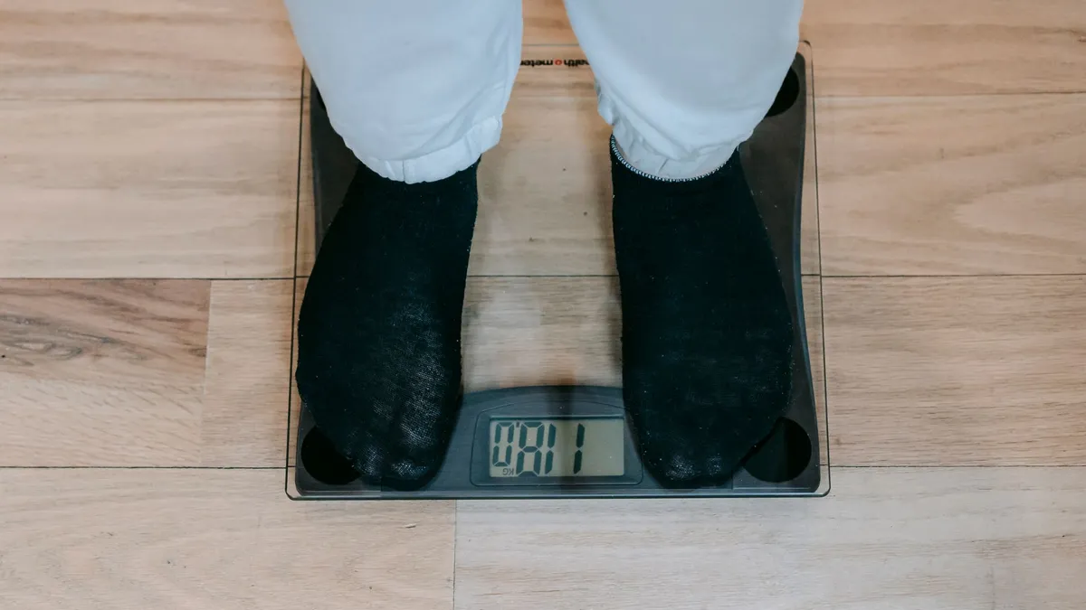 Person stepping onto a bathroom scale in the morning light