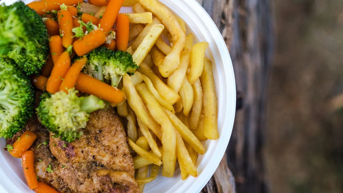 A balanced home-cooked dinner plate with chicken, grains and vegetables on a wooden table