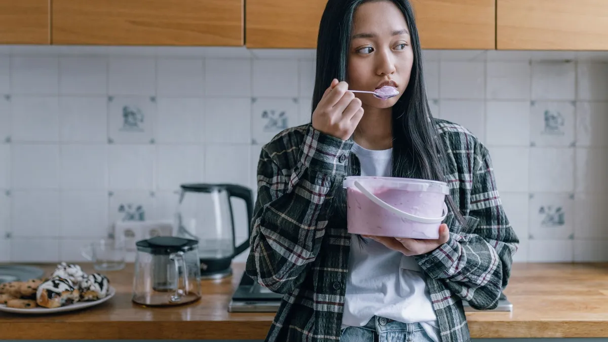 A person reaching into a kitchen cupboard for a snack