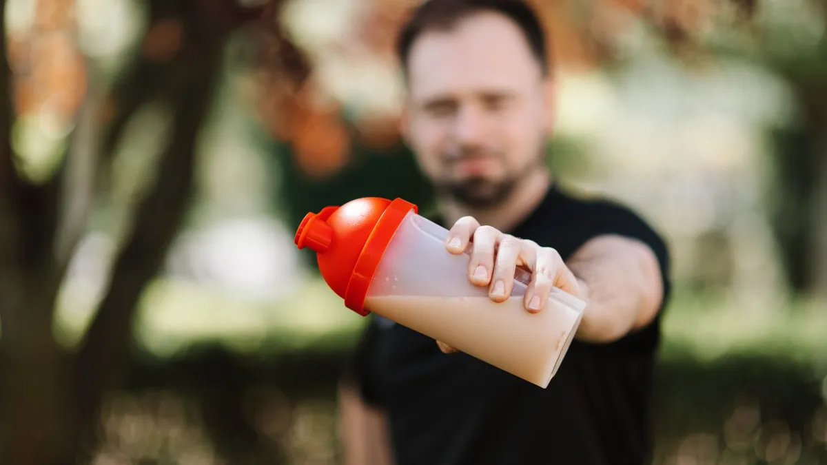 A person holding a protein shake after a workout at the gym