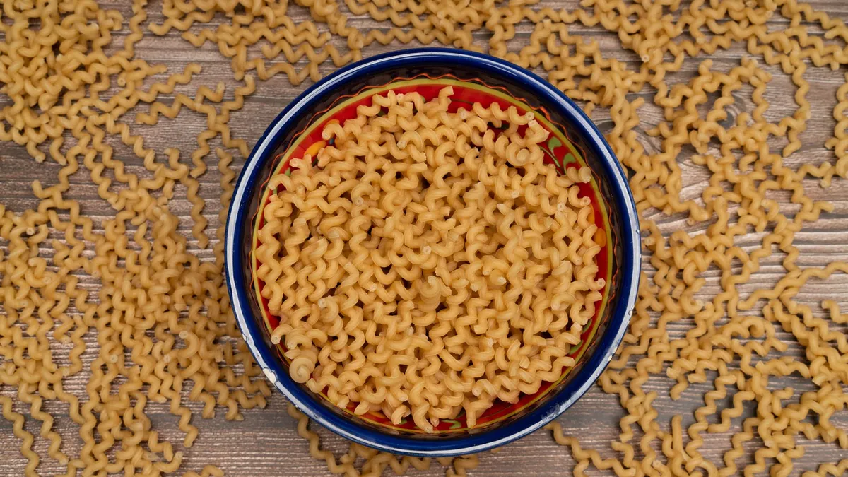 A large bowl of freshly cooked pasta on a wooden kitchen table