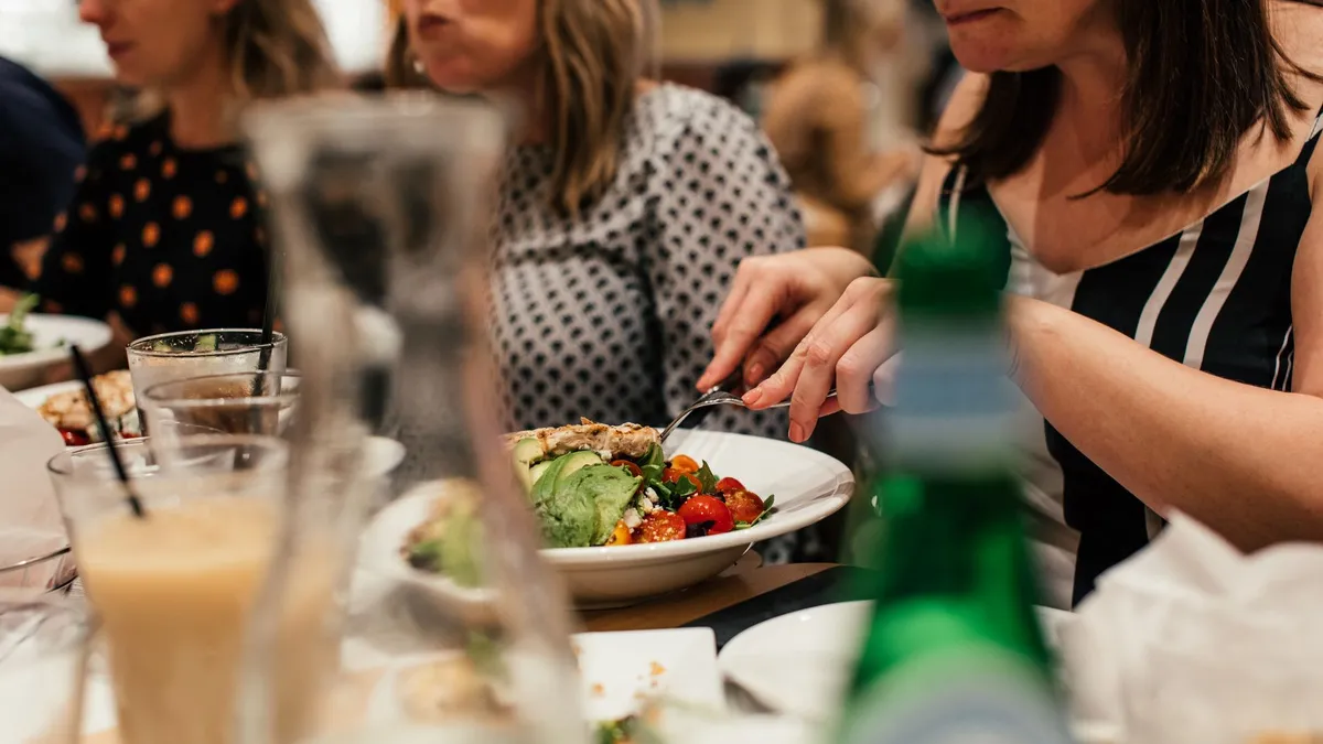 Une femme assise à une table de cuisine savourant un bol coloré de salade et de poulet grillé